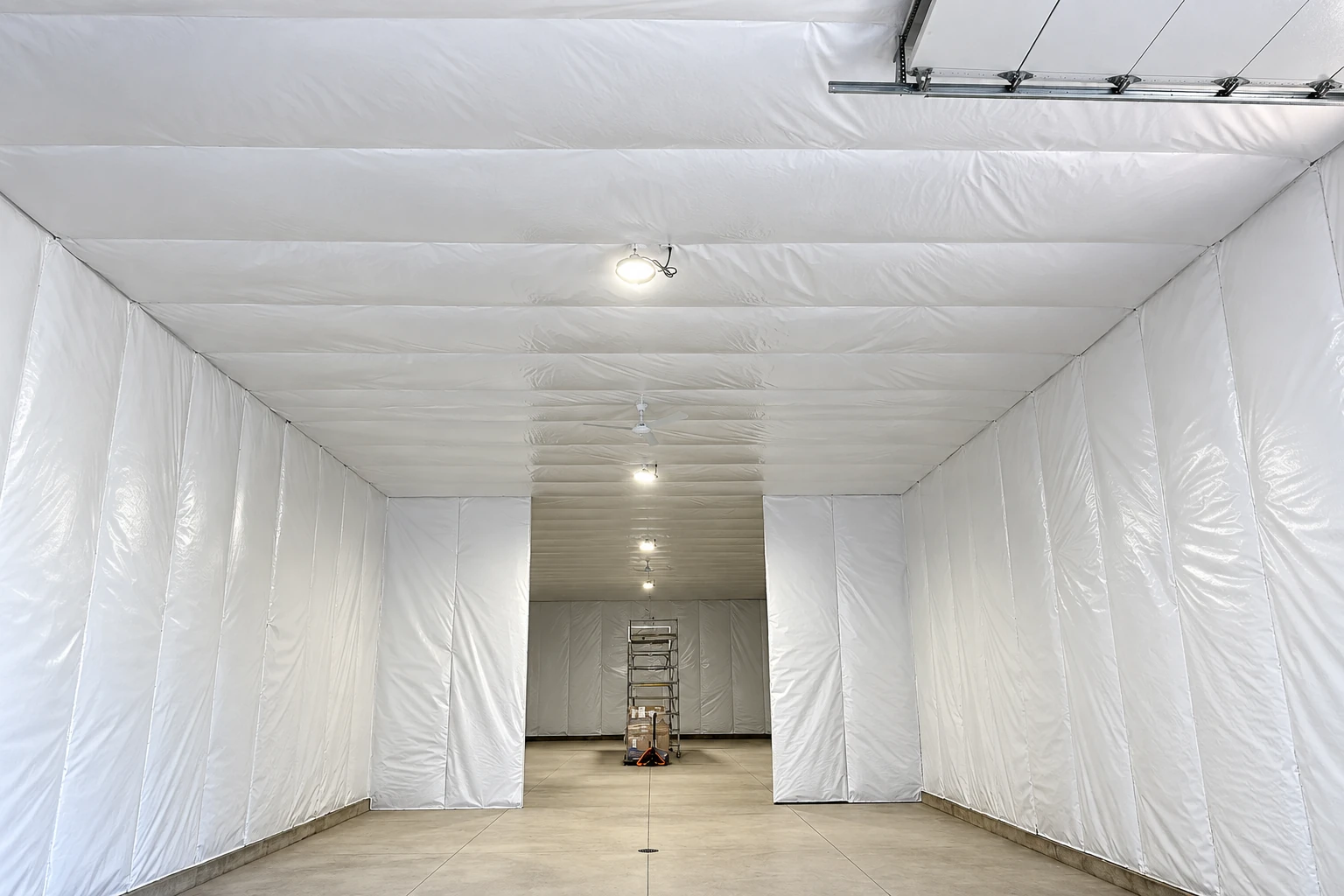 A large room is lined with white vapor barrier sheeting across its walls and ceiling.